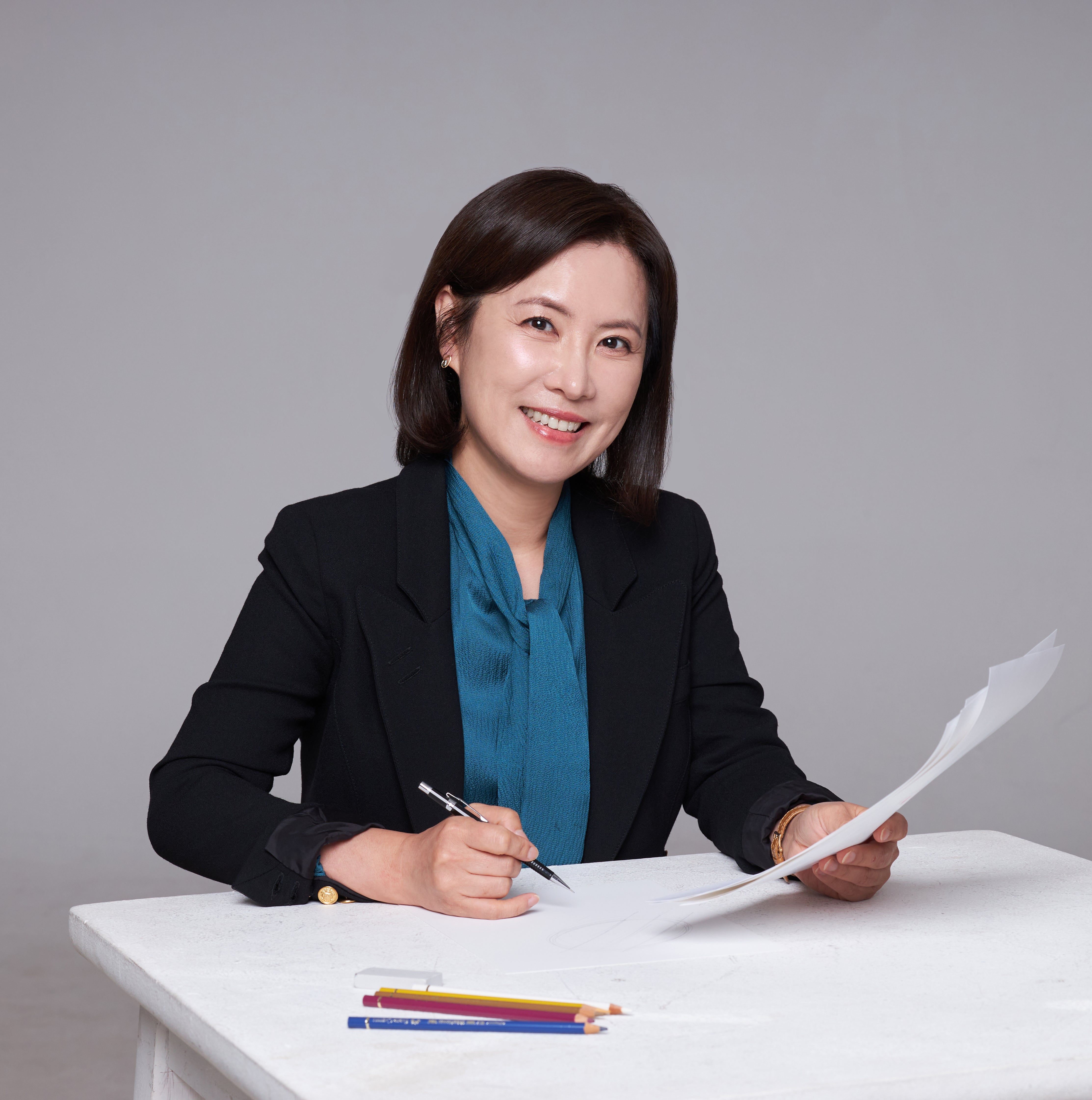 Headshot of Veniroe's designer, Gemma Park, smiling in a blue blouse and holding a pen