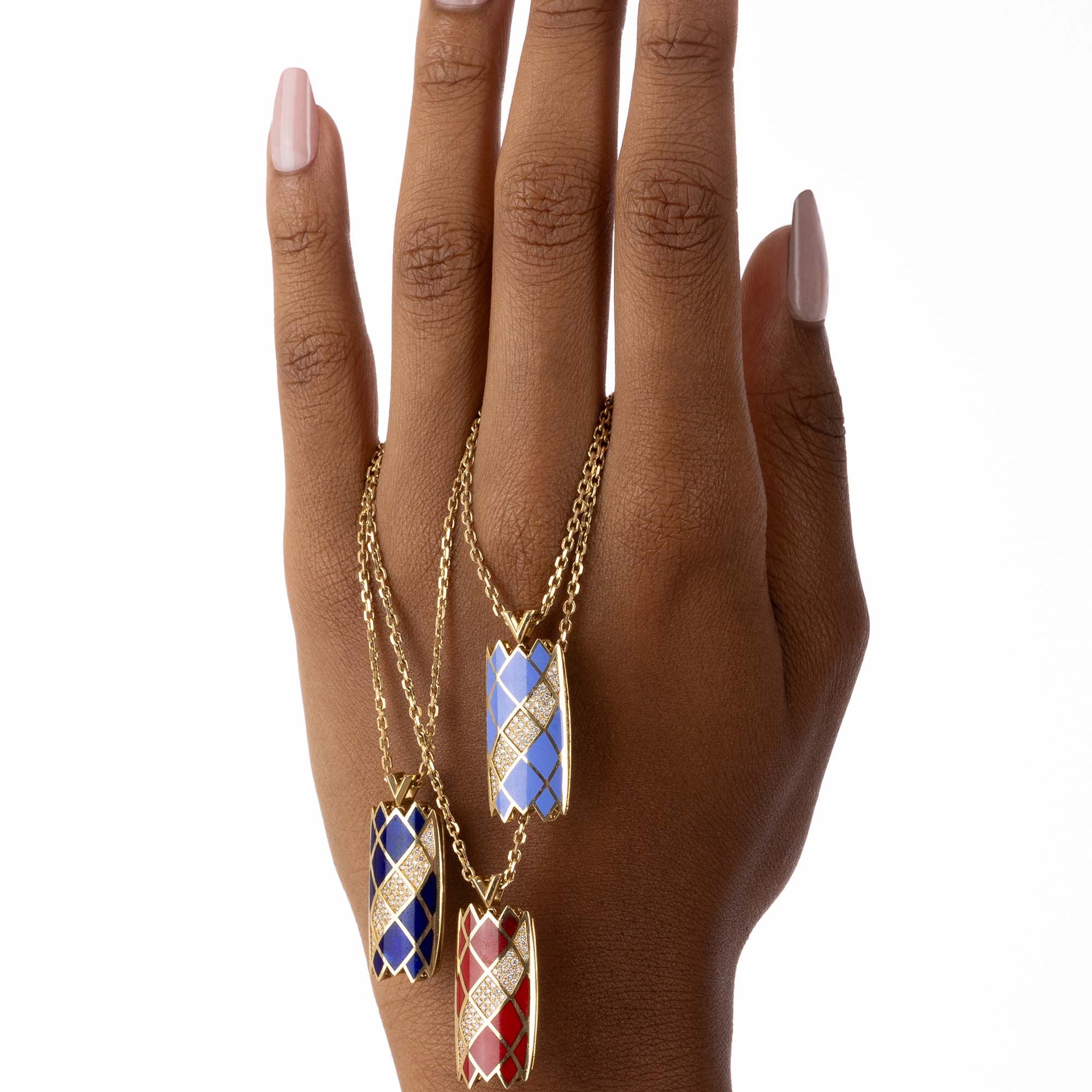 Three Castle Necklaces in light blue, dark blue, and red are draped over a model’s hand