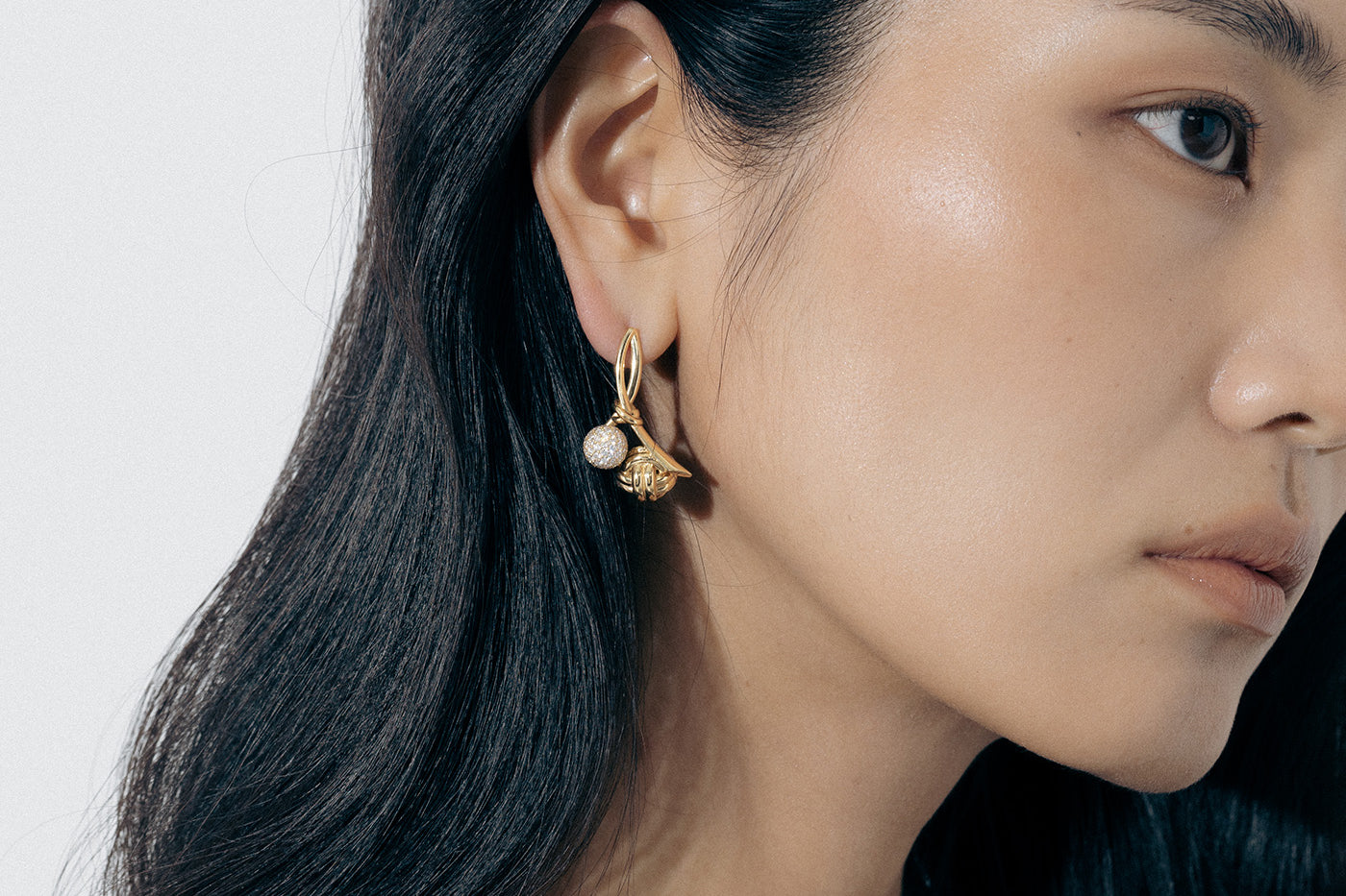 Yellow Gold ribbon shaped earrings with a macrame knot and Diamond encrusted ball - Model shot
