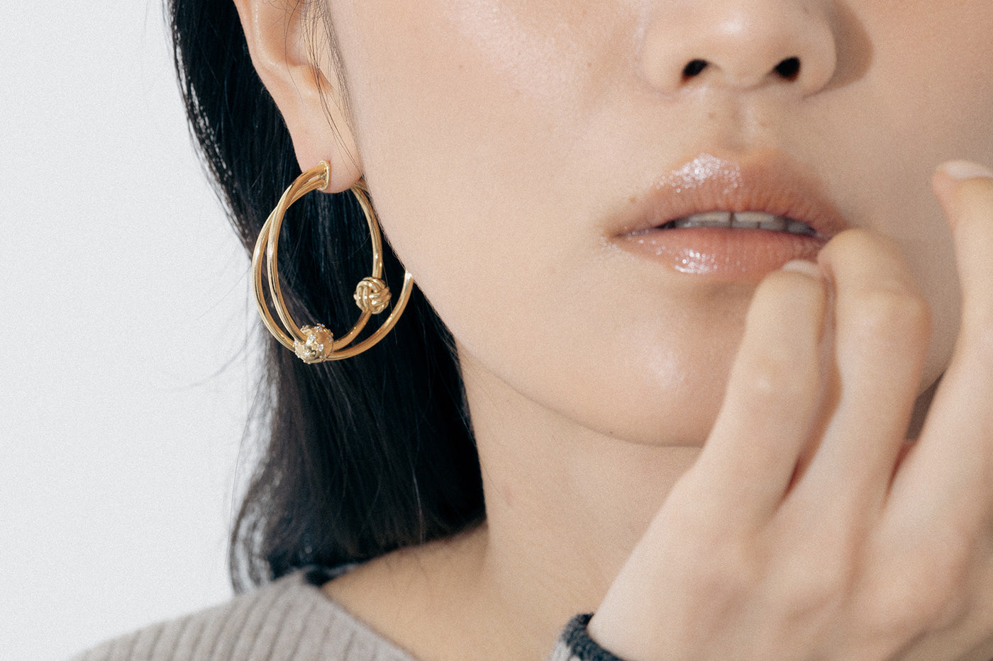 Yellow Gold earrings with linked hoops, a macrame knot, and a Diamond encrusted ball - Model shot