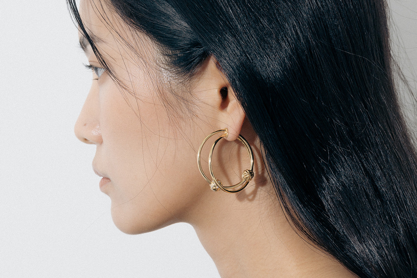 Yellow Gold earrings with linked hoops, a macrame knot, and a Diamond encrusted ball - Model shot