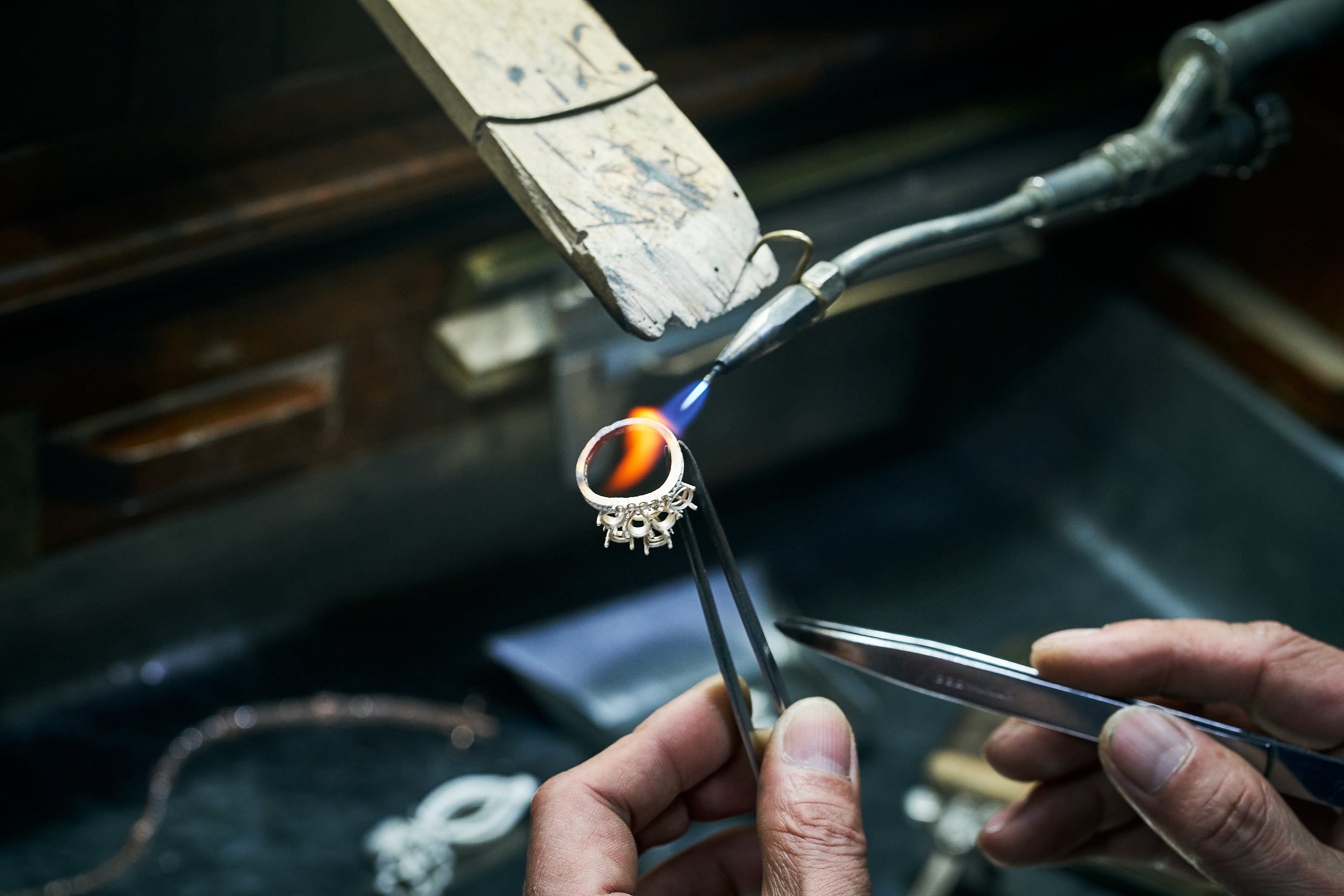 Ring held by tweezers as flame hits it from a small torch