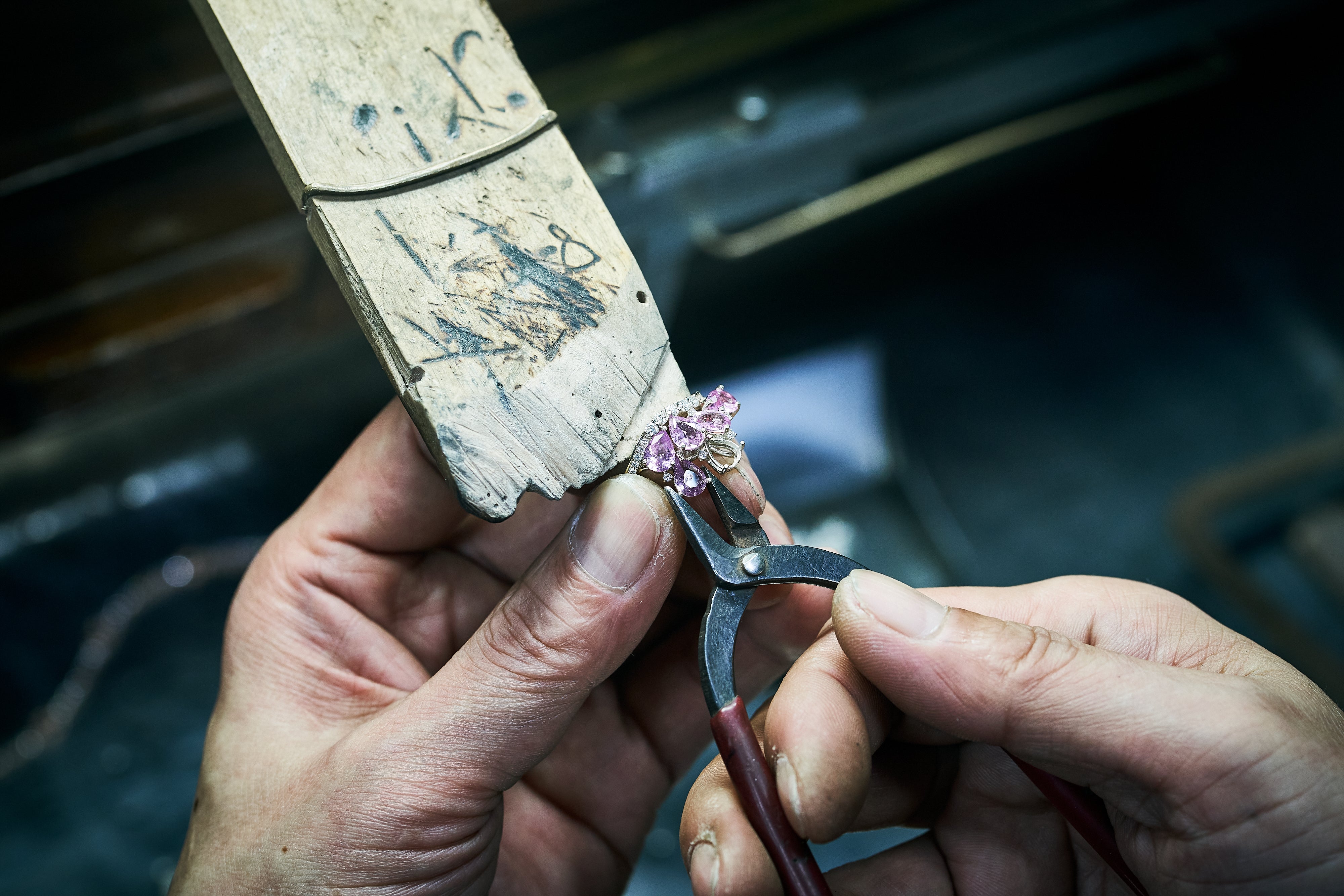 Pliers are used to adjust pink gemstone within ring frame