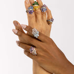 Twin Blossom Rings in various colors are worn across two hands of different skin tones