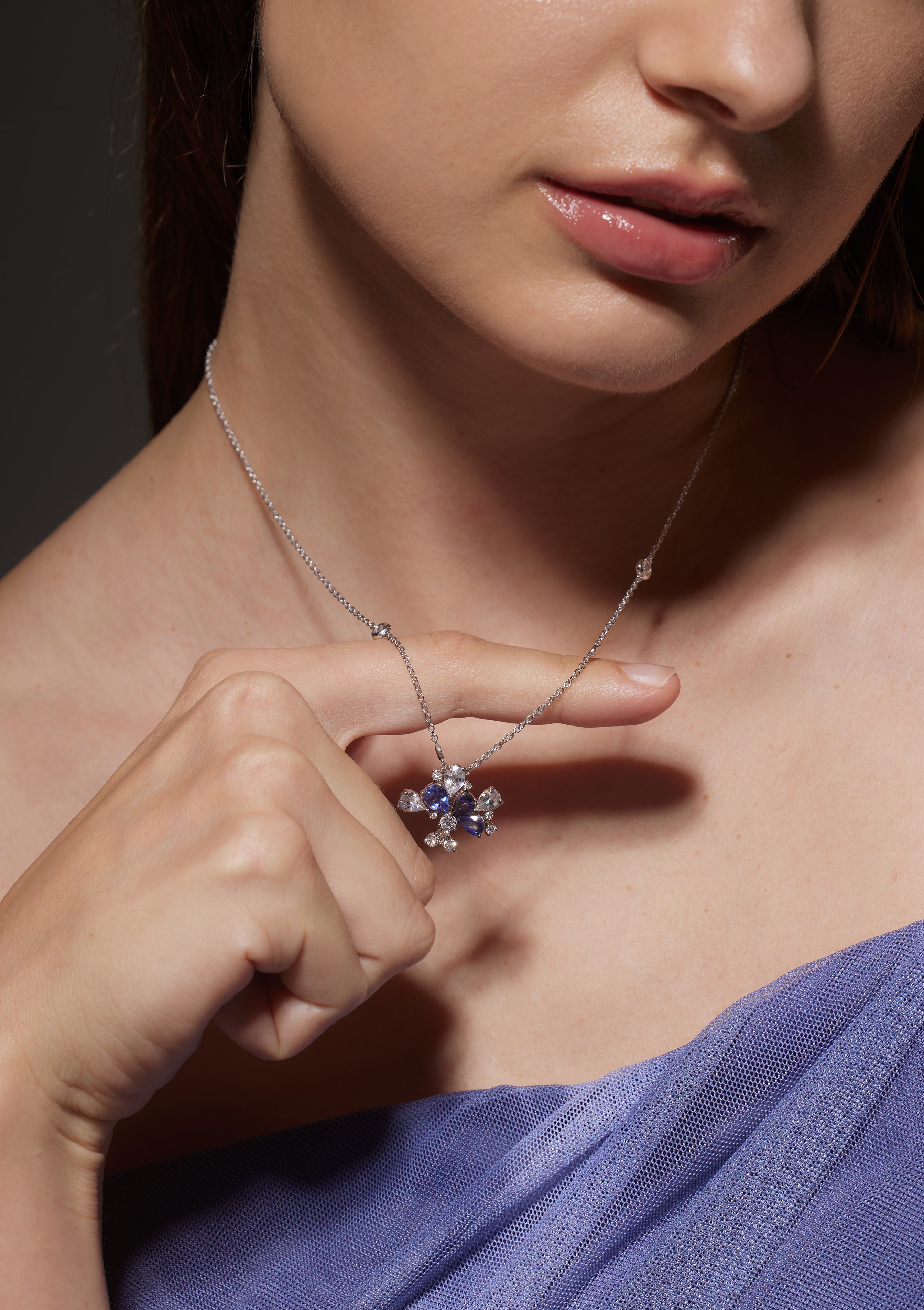 Model holds Willow Necklace in White Gold with Blue and White Sapphire, and Diamonds