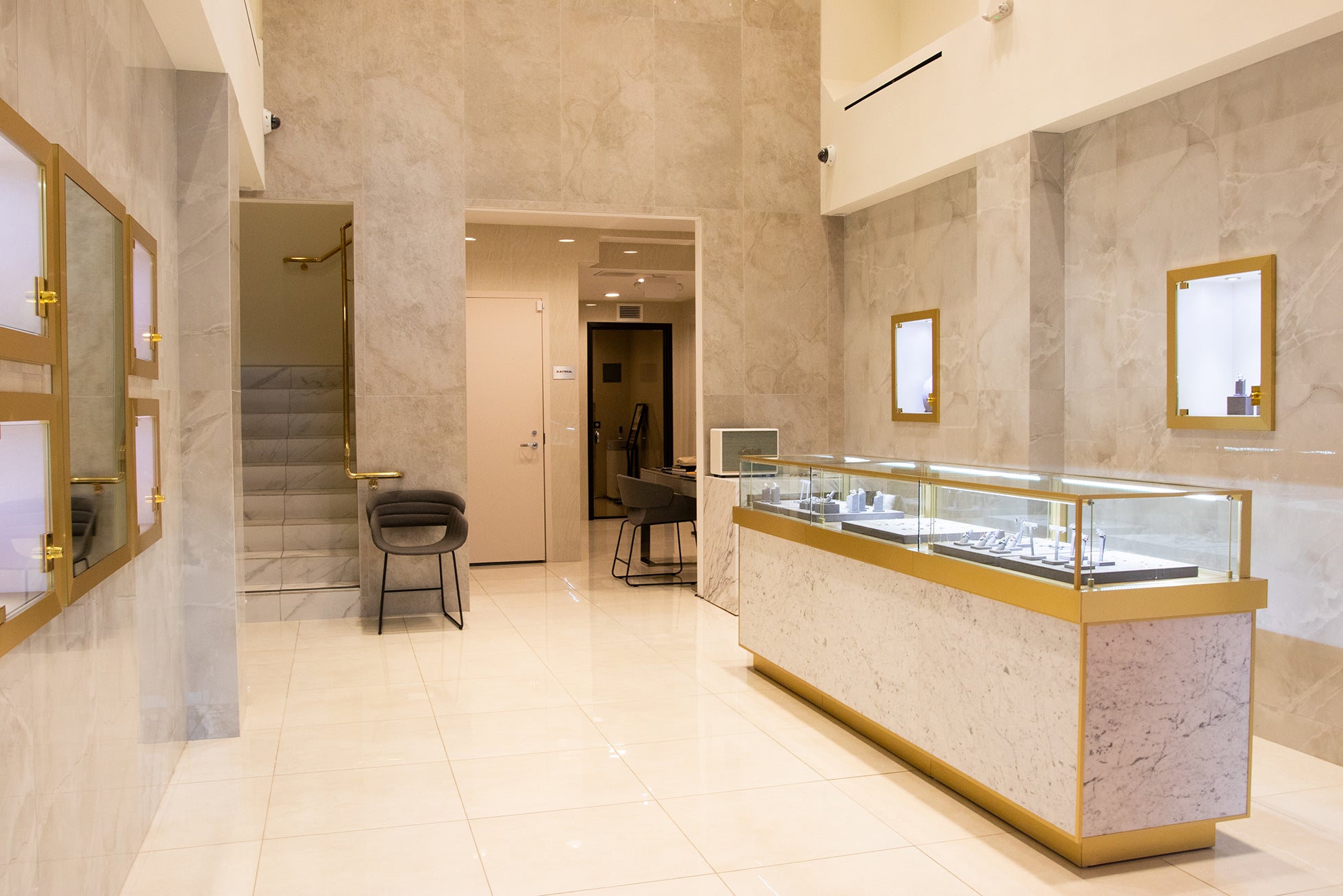 Bright interior of Veniroe’s boutique with light marble walls, golden trim, and coral velvet displays